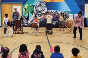 Children playing on drums in a gym